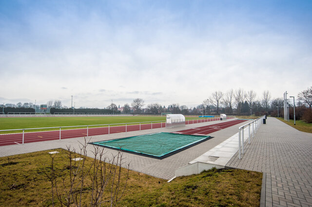 Fußballfeld und Sportpark mit Geländer in Weitwinkelaufnahme und blauer Horizont