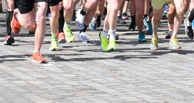 Startszene beim Citylauf in Sömmerda. Auf Granitpflaster sind die Beine von Läuferinnen und Läufern in verschiedenfarbigen Turnschuhen zu sehen. Sie sind gerade beim Start losgelaufen.