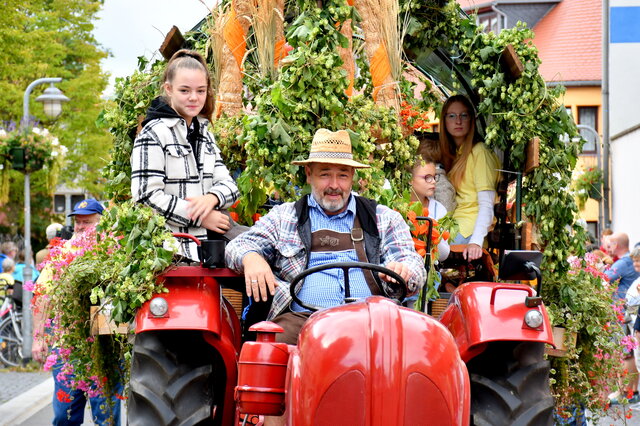 Ein roter geschmückter Traktor mit einem Bauern und einer jungen Frau