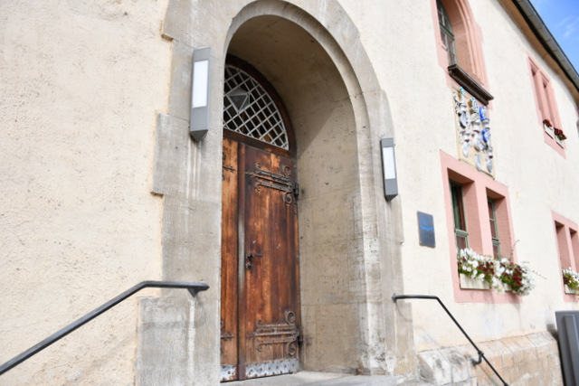 Die Rathaus-Vorderfront mit Eingangstür sowie Fenstern. In den Fenstern im Erdgeschoss stehen Blumenkästen.