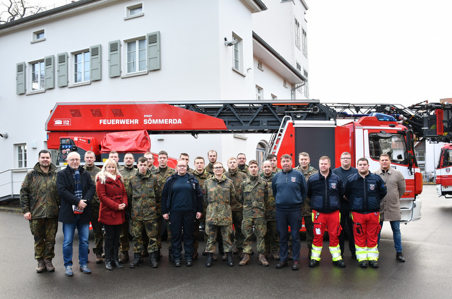 Bürgermeister, Vertreter der Stadtverwaltung, der Feuerwehr und der Patenkompanie stehen in zwei Reihen hintereinander auf dem Gelände der Feuerwache Sömmerda vor einem Fahrzeug mit Feuerwehrdrehleiter. Im Hintergrund steht ein mehrstöckiges Gebäude, das zur Feuerwache gehört.